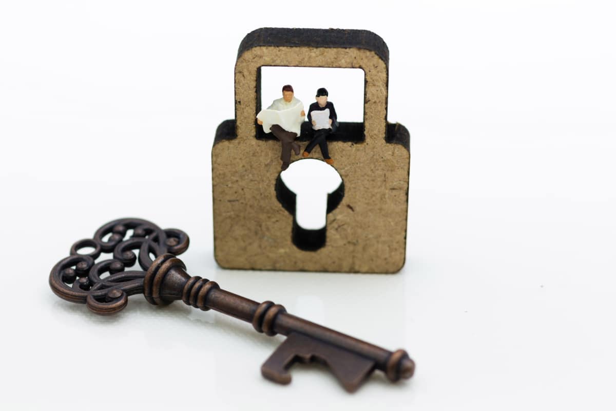 mini people sitting on a lock with key